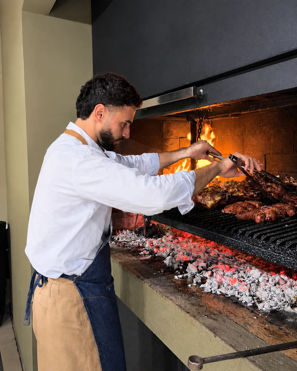 Roni, de Asarte, atendiendo la parrilla con las brasas encendidas